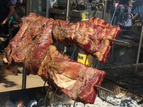 Costillar y cordero asándose al palo sobre las brasas