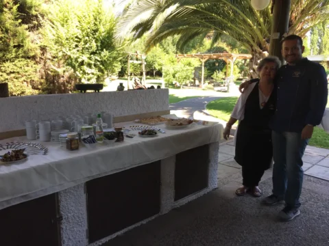 Anfitriones junto a la mesa de desayuno en un jardín