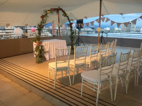 Sillas blancas y arco de flores para una ceremonia en terraza
