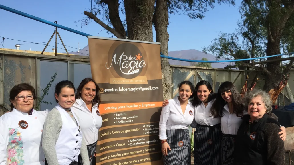 Equipo de Dulce Magia junto a su pendón en un evento al aire libre