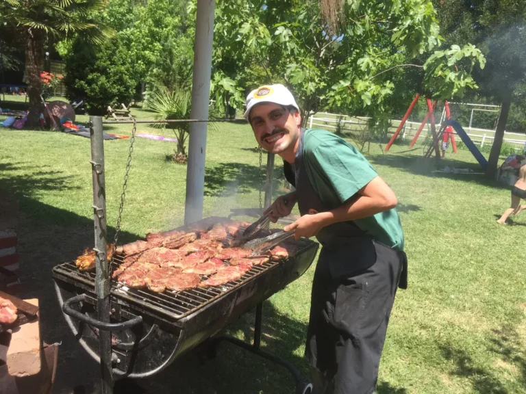 Parrillero preparando carne en una parrilla al aire libre